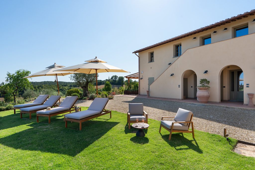 Zona relax sul prato con lettini e ombrelloni accanto al casolare di Castelforno.