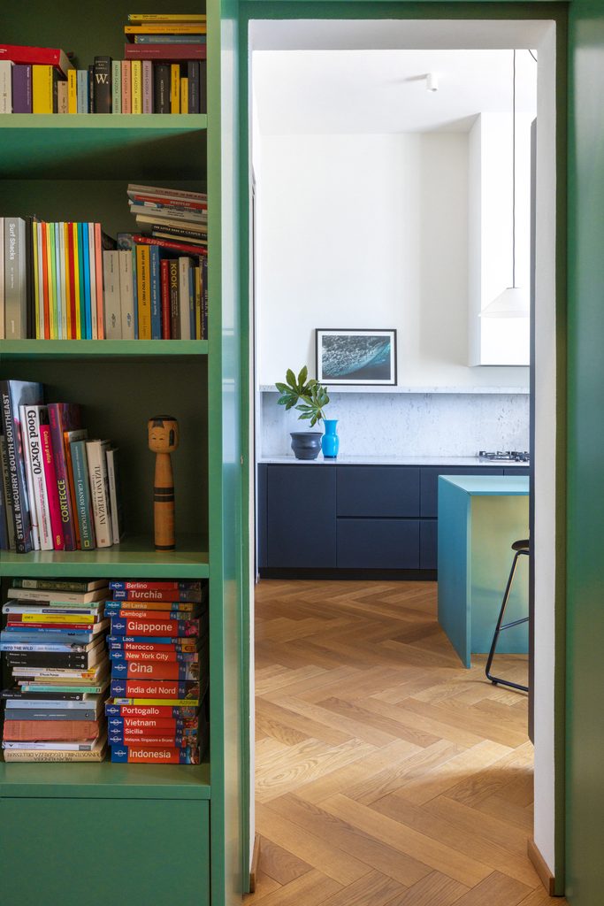 Libreria verde a tutta altezza attraversata dal passaggio verso la cucina.