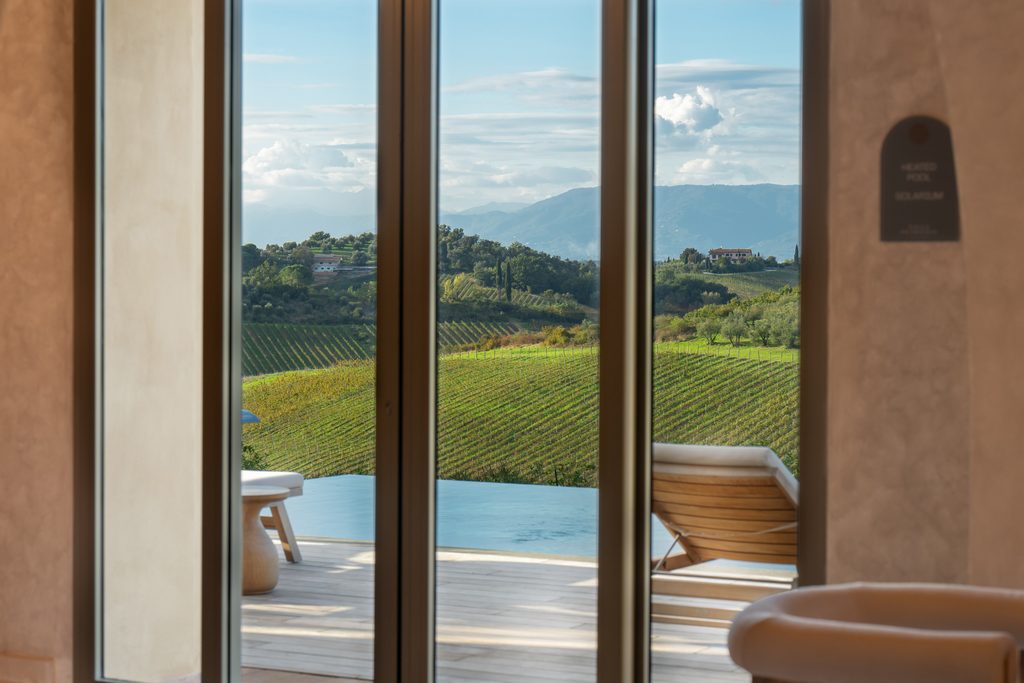 Vetrata del casale aperta sulla piscina a sfioro e sulle vigne.
